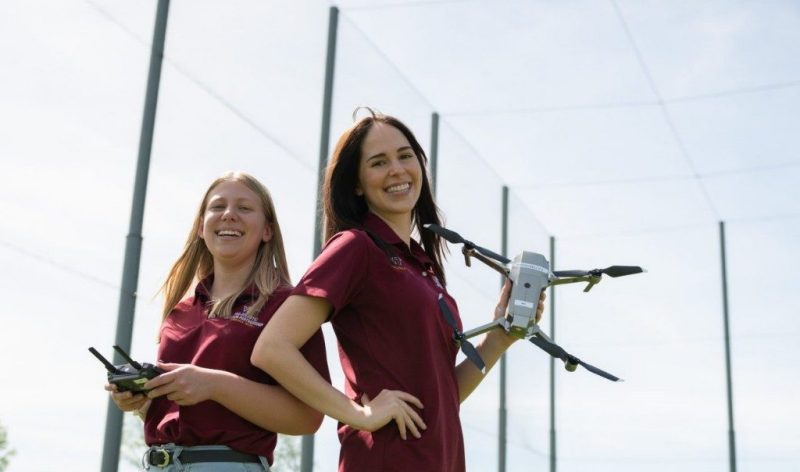 Two women, one holding a drone, the other a drone controller.
